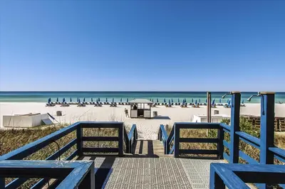 a beach with blue chairs and the ocean at 1202 Seychelles in Panama City Beach