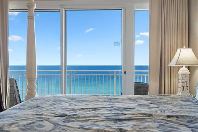 a bedroom with a bed and a view of the ocean at 1105 Sterling Beach in Panama City Beach