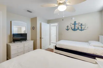 a bedroom with two beds and a flat screen tv at 305 Sterling Beach in Panama City Beach
