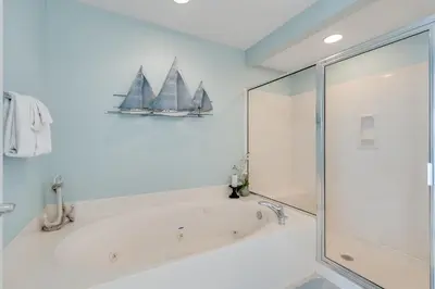 a bathroom with a bath tub with two sailboats on the wall at 305 Sterling Beach in Panama City Beach
