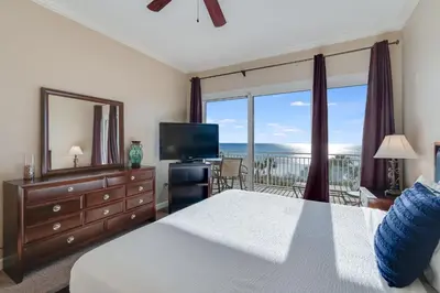a bedroom with a bed and a television and a balcony at 305 Sterling Beach in Panama City Beach