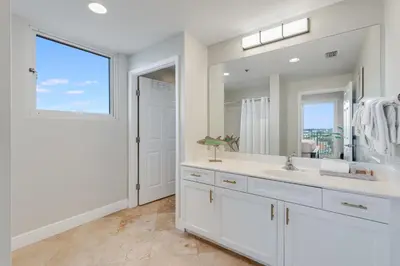 a white bathroom with a sink and a large mirror at 607 Sterling Beach in Panama City Beach