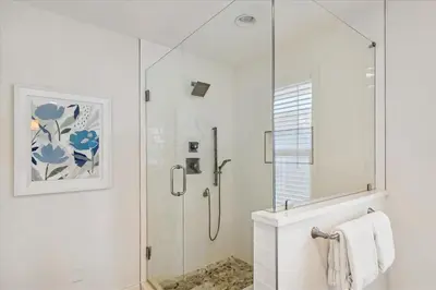 a white bathroom with a shower with a glass door at The Southern Yankee in Panama City Beach
