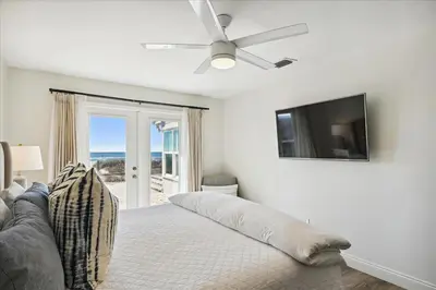a white bedroom with a bed with a ceiling fan at The Southern Yankee in Panama City Beach