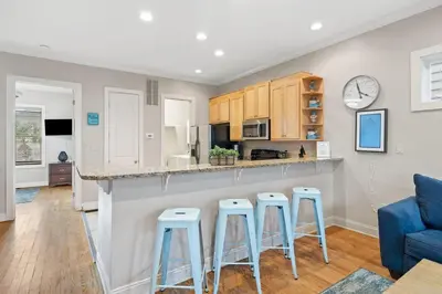 a kitchen with a bar and stools in a living room at Sunset Serenity in Panama City Beach