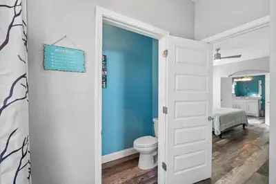 a bathroom with a toilet and a blue wall at Hilltop Manor in Panama City Beach