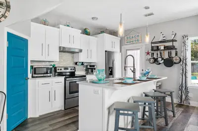 a kitchen with white cabinets and a blue door at Hilltop Manor in Panama City Beach
