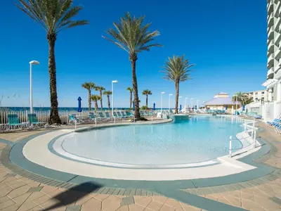 a swimming pool with palm trees and the ocean at Boardwalk #1602 in Panama City Beach