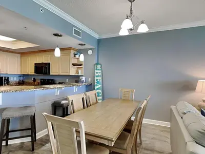 a dining room and kitchen with a wooden table and chairs at Boardwalk #1602 in Panama City Beach