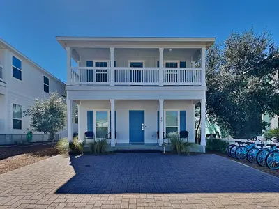 a white house with a balcony and bikes parked in front at Southern Charm in Inlet Beach