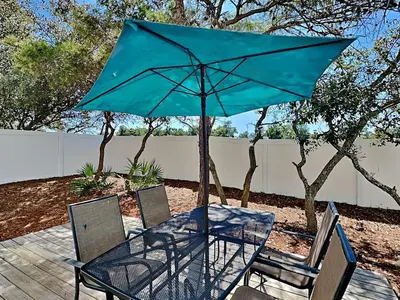a table with a blue umbrella and two chairs at Southern Charm in Inlet Beach