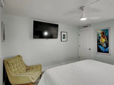a bedroom with a bed and a chair and a flat screen tv at Regency Towers PCB #1006 in Panama City Beach
