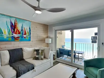 a living room with a couch and a view of the ocean at Regency Towers PCB #1006 in Panama City Beach