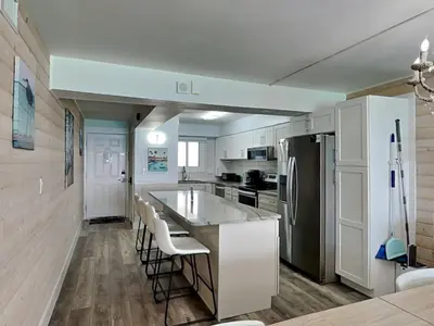 a kitchen with white cabinets and a large island with bar stools at Regency Towers PCB #1006 in Panama City Beach