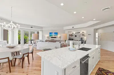 a kitchen and living room with white cabinets and a table at 37 Compass Point South #107 in Inlet Beach