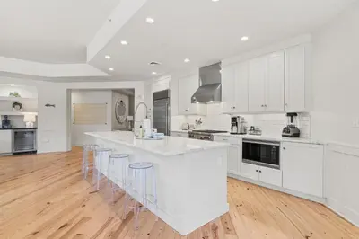 a kitchen with white cabinets and a large island with bar stools at 37 Compass Point South #107 in Inlet Beach