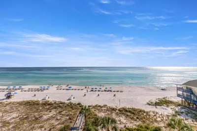 a beach with chairs and umbrellas and the ocean at Commodore 0607 in Panama City Beach