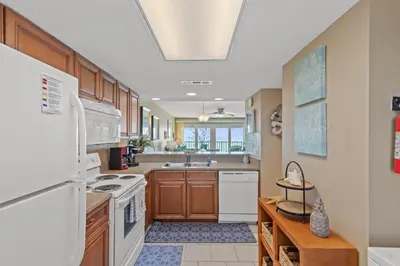 a kitchen with wooden cabinets and a white refrigerator at Commodore 0607 in Panama City Beach