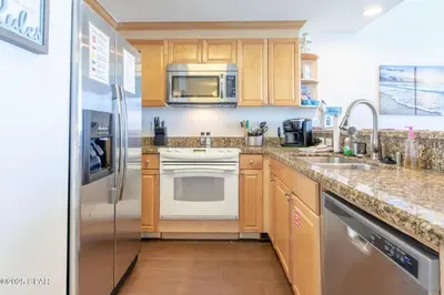 a kitchen with wooden cabinets and a stainless steel refrigerator at Boardwalk 2205 in Panama City Beach