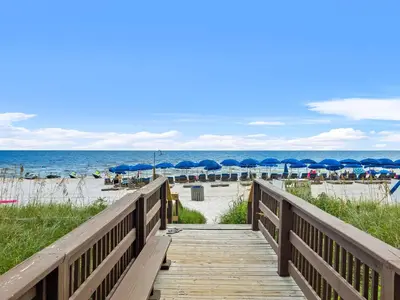 a wooden boardwalk leading to the beach with umbrellas at Celadon #0606 in Panama City Beach