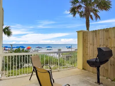 a balcony with chairs and a grill and the beach at Celadon #0606 in Panama City Beach