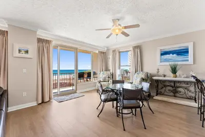 a living room with a table and chairs and a balcony at Hidden Dunes #201 in Panama City Beach
