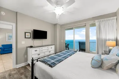 a bedroom with a bed with a television and a balcony at Treasure Island #2303 in Panama City Beach