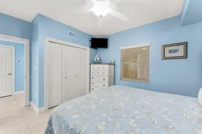 a blue bedroom with a bed and a dresser at Treasure Island #0106 in Panama City Beach