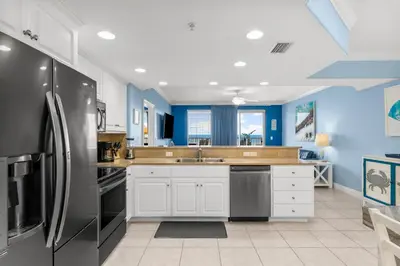 a kitchen with blue walls and a refrigerator at Treasure Island #0106 in Panama City Beach