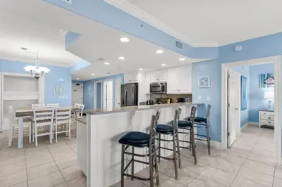 a kitchen with blue walls and bar stools at Treasure Island #0106 in Panama City Beach