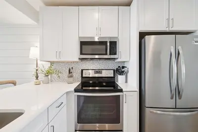 a kitchen with white cabinets and a stainless steel refrigerator at HP 34W On the Shore by 30A Escapes in Rosemary Beach