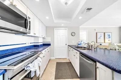 a kitchen with white cabinets and blue counter tops at Seachase E301 by Emerald Coast Retreats in Panama City Beach