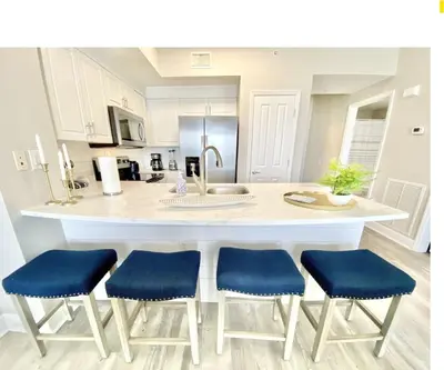 a kitchen with a large white island with blue chairs at Celadon 405 by Emerald Coast Retreats in Panama City Beach