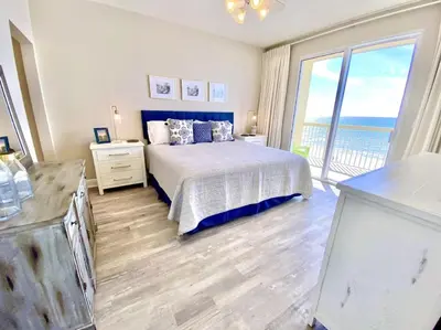 a bedroom with a bed and a balcony with the ocean at Celadon 405 by Emerald Coast Retreats in Panama City Beach