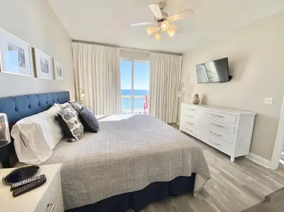 a bedroom with a bed and a dresser with a window at Celadon 405 by Emerald Coast Retreats in Panama City Beach