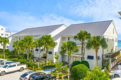 a white house with palm trees in front of it at 30A Eastern Shores Condominiums by Panhandle Getaways in Santa Rosa Beach