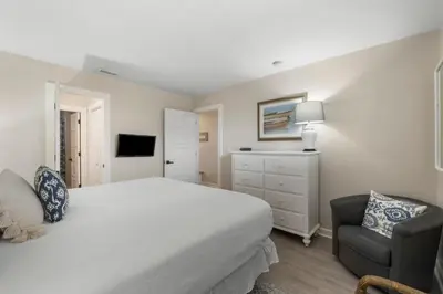 a white bedroom with a bed and a chair at 30A Eastern Shores Condominiums by Panhandle Getaways in Santa Rosa Beach