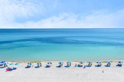 a group of chairs and umbrellas on a beach at 30A Eastern Shores Condominiums by Panhandle Getaways in Santa Rosa Beach