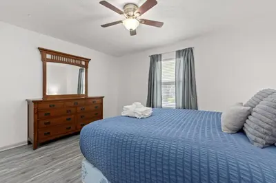 a bedroom with a blue bed and a ceiling fan at Bombastic Beach Bungalow, 10 Min WALK to the Beach in Panama City Beach
