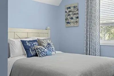 a bedroom with blue walls and a bed with pillows at Bombastic Beach Home, HOT TUB, 8min WALK to Beach in Panama City Beach
