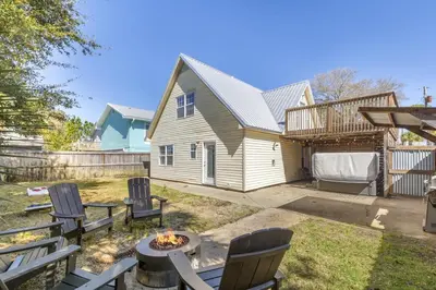 a backyard with chairs and a fire pit and a house at Bombastic Beach Home, HOT TUB, 8min WALK to Beach in Panama City Beach
