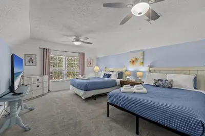 a bedroom with two beds and a flat screen tv at Bombastic Beach Home, HOT TUB, 8min WALK to Beach in Panama City Beach