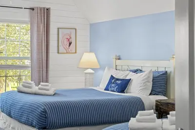 a blue and white bedroom with a bed and a window at Bombastic Beach Home, HOT TUB, 8min WALK to Beach in Panama City Beach