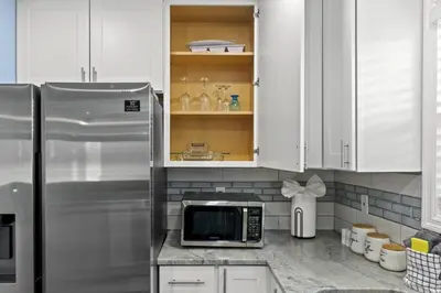a kitchen with white cabinets and a microwave at Bombastic Beach Home, HOT TUB, 8min WALK to Beach in Panama City Beach