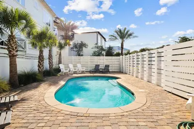 a swimming pool in a backyard with a fence and palm trees at Saltwater Therapy on 30A by 30A Escapes in Seacrest