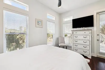 a white bedroom with a large bed and a flat screen tv at Saltwater Therapy on 30A by 30A Escapes in Seacrest