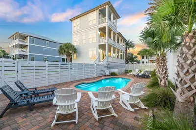 a patio with chairs and a pool and a house at Saltwater Therapy on 30A by 30A Escapes in Seacrest