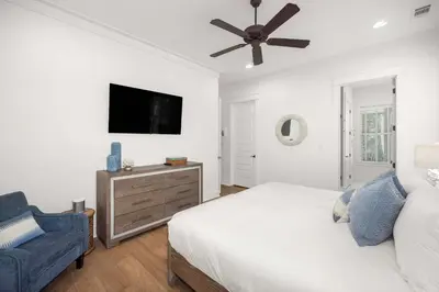 a bedroom with a bed and a tv and a chair at Seagrove Escape Refreshed plus Shared Pool in Seagrove Beach