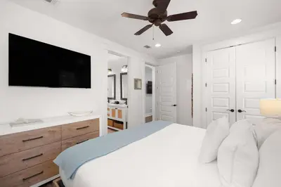 a white bedroom with a bed and a ceiling fan at Seagrove Escape Refreshed plus Shared Pool in Seagrove Beach