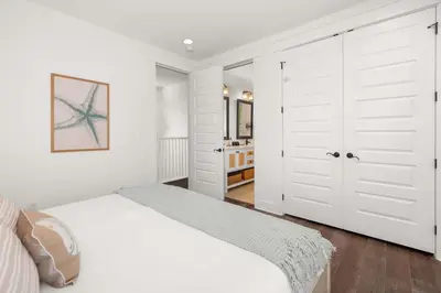 a white bedroom with a bed and two white doors at Seagrove Escape Refreshed plus Shared Pool in Seagrove Beach